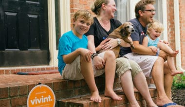 family sitting on the front step of their home with a dog