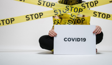woman holding COVID19 sign with "stop" caution tape everywhere