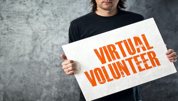 man holding banner that says virtual volunteer