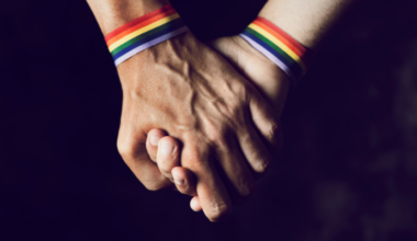 two people holding hands with pride bracelets on